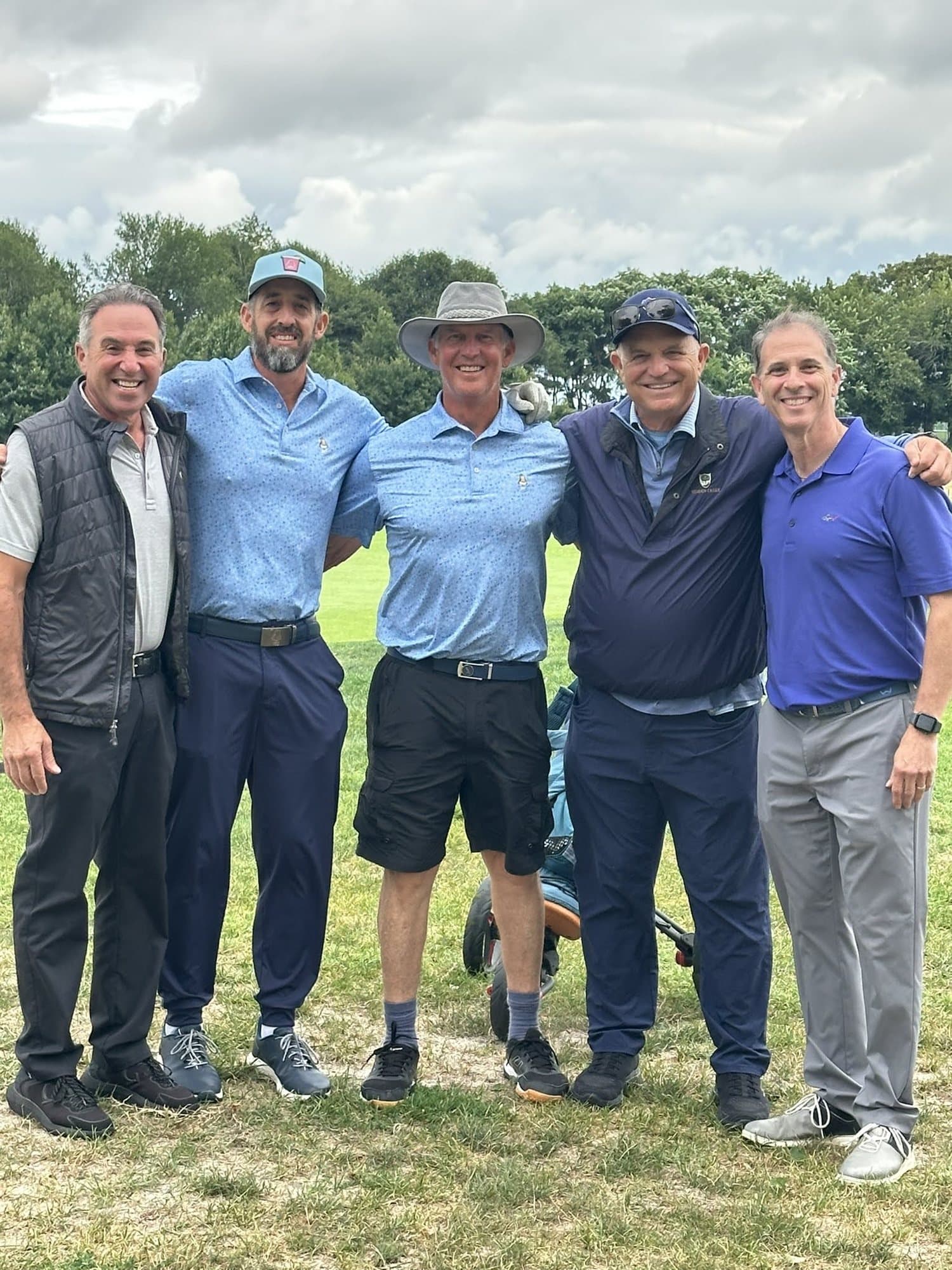 Five golfers standing together on the course