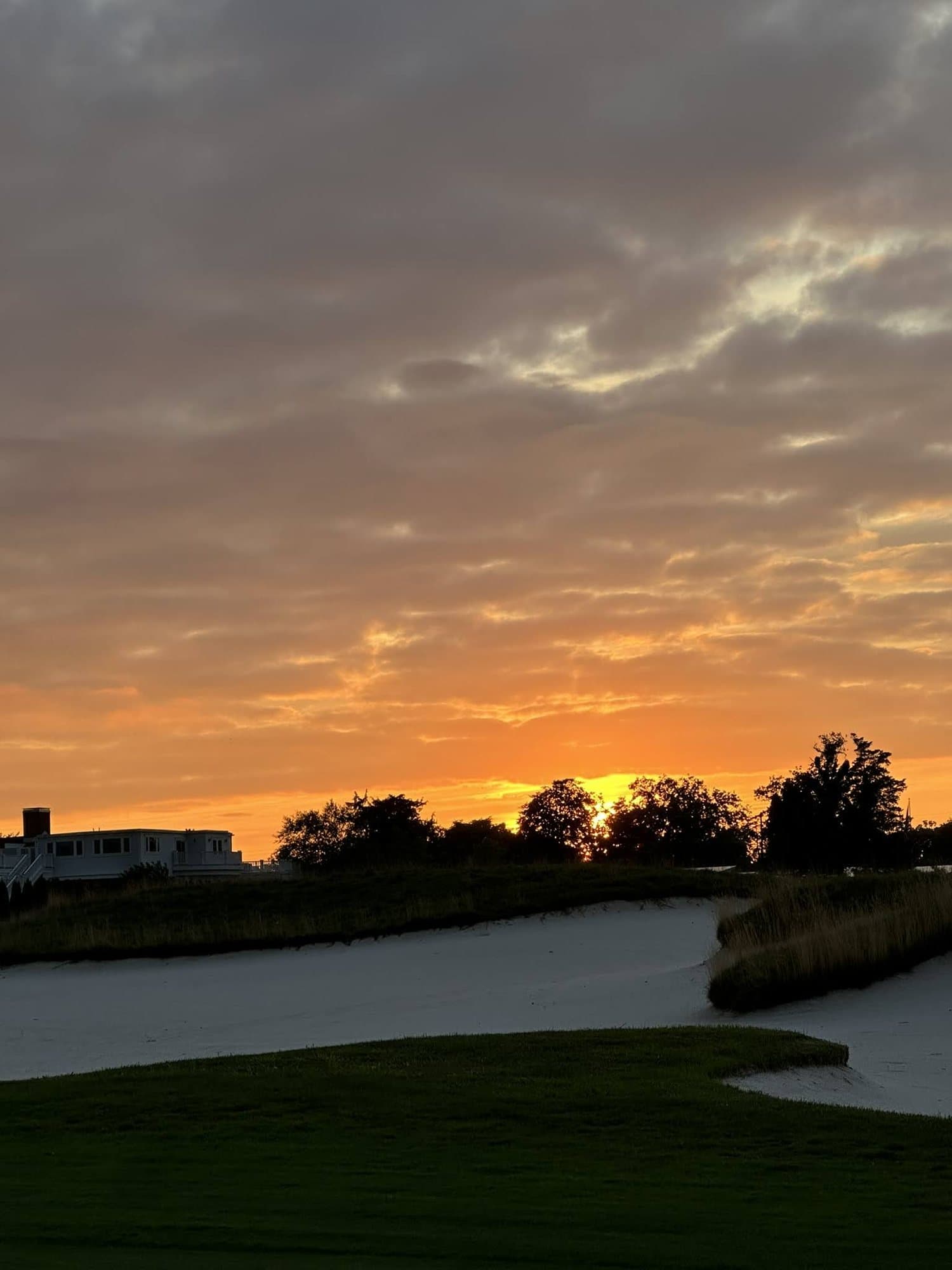 The sun going down behind a greenside bunker